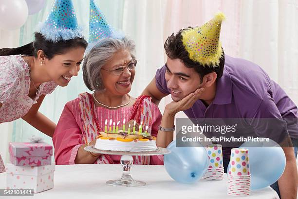 woman celebrating birthday with grandchildren - light vivid children senior young focus foto e immagini stock