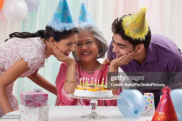 woman celebrating birthday with grandchildren - light vivid children senior young focus foto e immagini stock