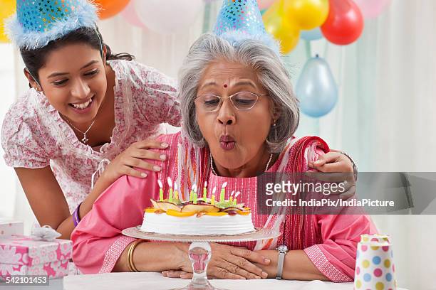 woman celebrating birthday with granddaughter - light vivid children senior young focus foto e immagini stock
