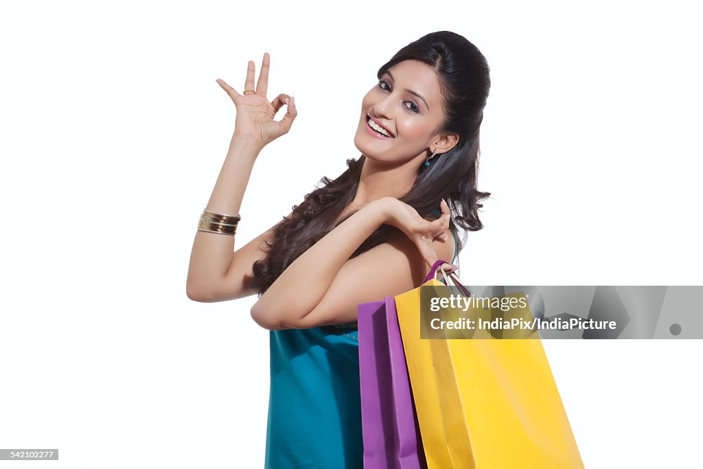 Portrait of a woman with shopping bags giving ok sign