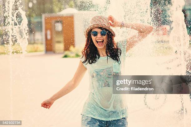 girl having fun in a water fountain - drinkwaterfontein stockfoto's en -beelden