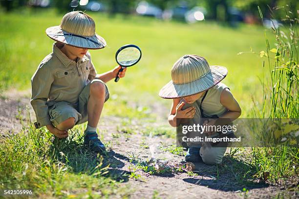 little safari boys making fire with magnification glass - safari stockfoto's en -beelden