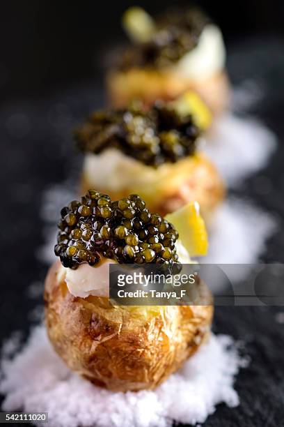 baked potatoes with black caviar - amuse bouche stockfoto's en -beelden