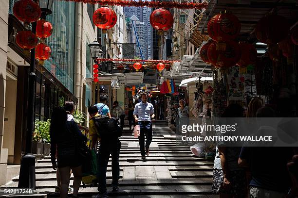 An expatriate walks past stalls in an old market in the Central district of Hong Kong on June 22, 2016. Hong Kong was named the worlds most expensive...