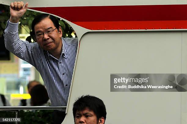 Japanese Communist Party chairman Kazuo Shii waves to voters from the campaign bus during his party election campaign for the upcoming upper house...