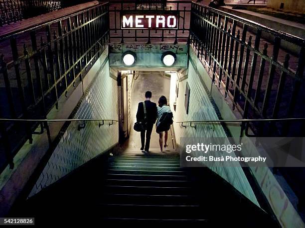 couple of young people entering a station of the paris metro at night. paris, france - sinal do metrô sinal informativo - fotografias e filmes do acervo