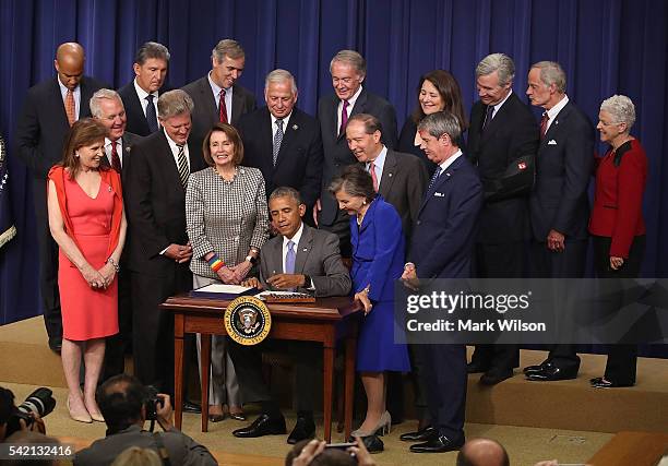President Barack Obama is flanked by members of Congress as he signs the HR 2576 bill during an event in the Eisenhower Executive Office Building,...