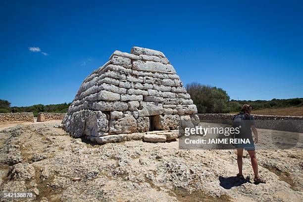 Tourist walks past the Naveta des Tudons, a prehistoric monument near the Ciutadella on the island of Menorca on June 22, 2016. Human presence in...
