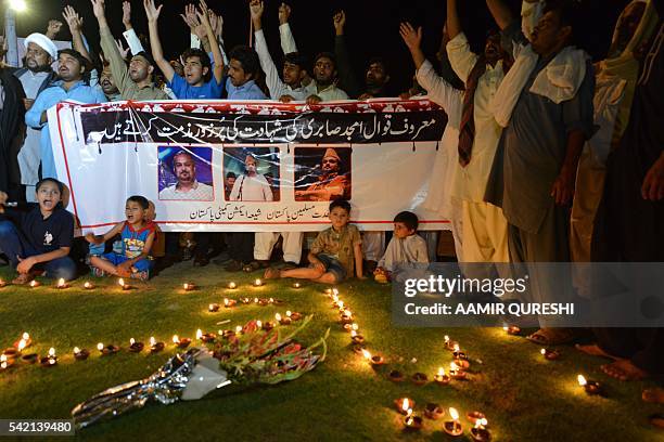 Pakistani Shiite Muslim protesters shout slogans beside lighted oil lamp to pay tribute to Sufi musician Amjad Sabri who was killed in an attack by...