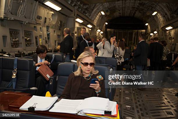 Secretary of State Hillary Clinton, aboard a C-17, checking her PDA in sunglasses upon departure from Malta bound for a meeting with rebel leaders in...