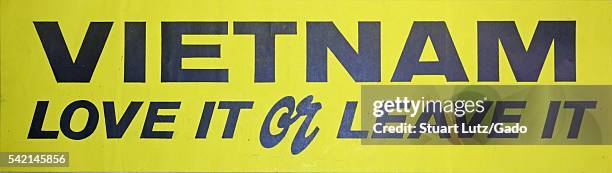 Vietnam War era bumpersticker that has a yellow background and black lettering that reads 'Vietname love it or leave it', 1970. .