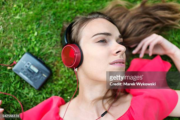 young woman lying on the lawn in a park and listening to music on walkman. - personal cassette player stockfoto's en -beelden