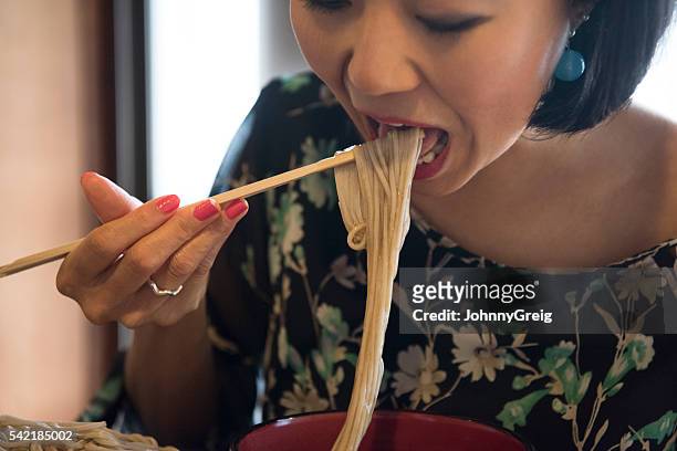 mid adult japanese woman eating noodles, mouth open - soba stock pictures, royalty-free photos & images
