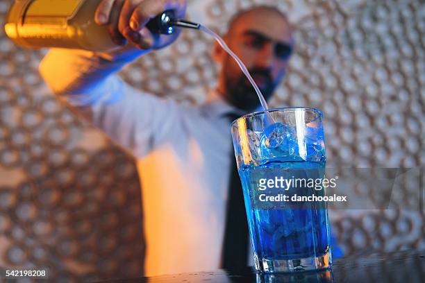 barkeeper cocktail machen - blue martini glasses stock-fotos und bilder