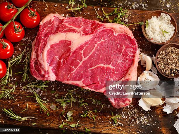 rohes rippenauge steak mit frischen kräutern - rib eye steak stock-fotos und bilder