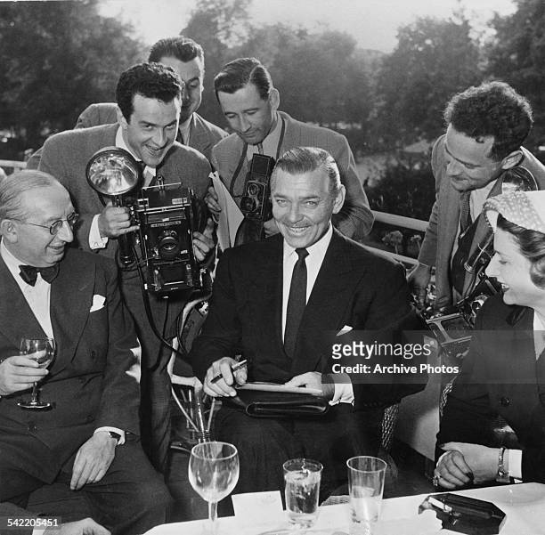 American actor Clark Gable surrounded by photographers, circa 1955. One is holding a Speed Graphic camera.