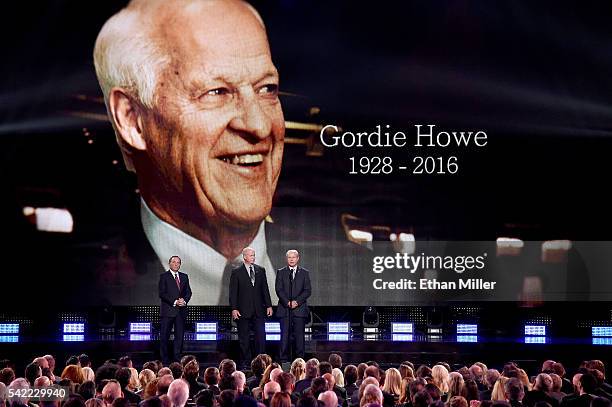 Commissioner Gary Bettman stands with Mark Howe and Marty Howe as they speak during the In Memoriam portion of the show as a picture of their father...