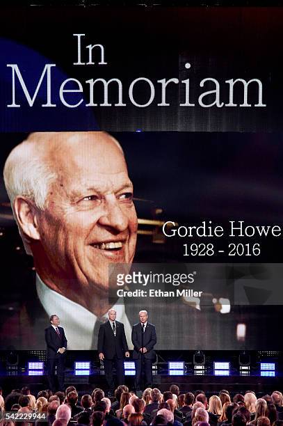 Commissioner Gary Bettman stands with Mark Howe and Marty Howe as they speak during the In Memoriam portion of the show as a picture of their father...