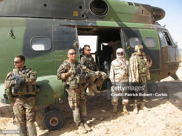 Soldiers of the army of Chad standing next to an helicopter of the French Special Forces.