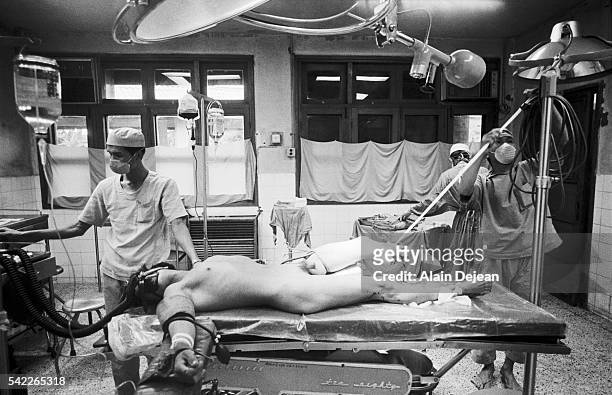 Wounded soldier is amputated in a makeshift operating theater during the Vietnam War.