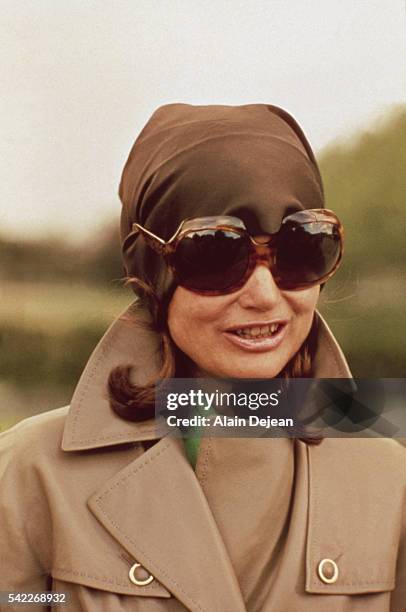 Former First Lady of the United States Jacqueline Kennedy Onassis wears dark sunglasses and a kerchief to protect her privacy.