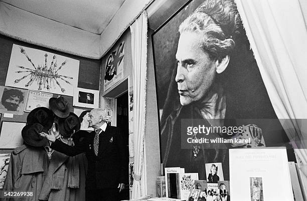 French writer and poet Louis Aragon at home with a photograph of his partner, poet, translator and writer Elsa Triolet, behind him.