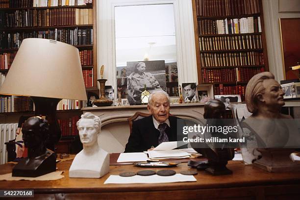 French writer and poet Louis Aragon at home with a photograph of his partner, poet, translator and writer Elsa Triolet, behind him.