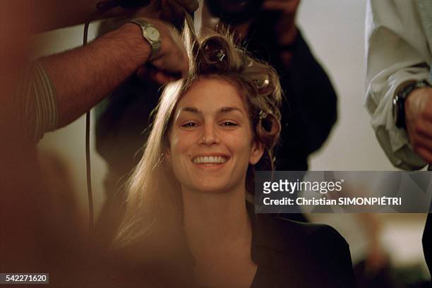 American supermodel Cindy Crawford laughs as stylists apply makeup and set her hair.