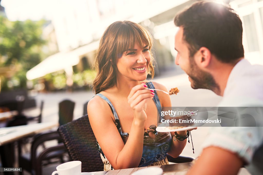 Lovely couple enjoying dessert in cafe .