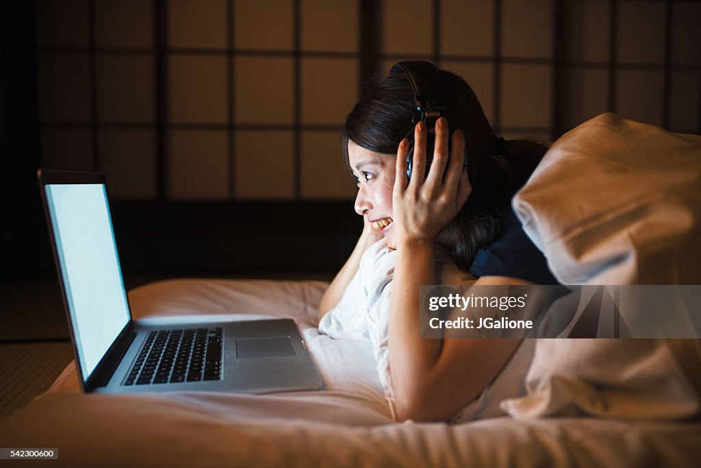 Young woman using computer in bed