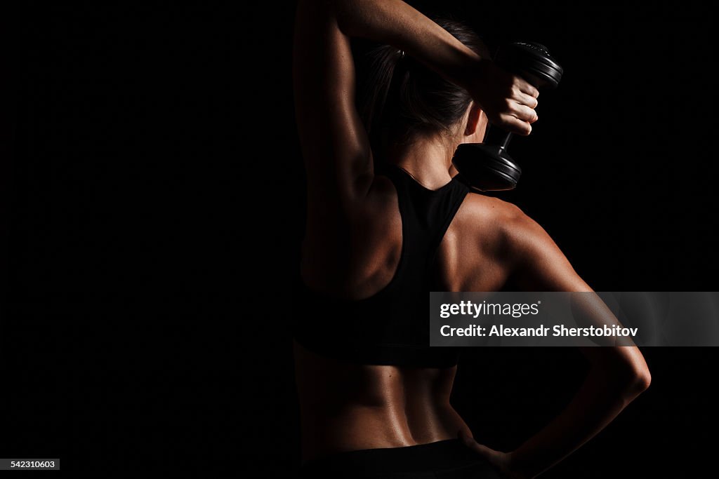 Rare view of female body, exercising with dumbbell