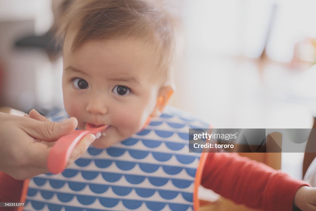 Eurasian baby girl being fed with spoon