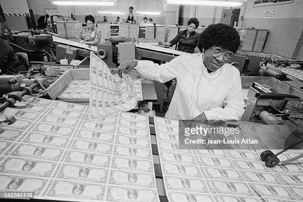 Factory worker separates sheets of freshly printed dollar bills in a currency printing factory.