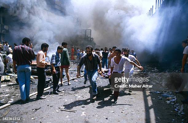 Four men desperately running with a stretcher bearing a wounded victim of a car bomb explosion in the Muslim quarter of Beirut, while in the...