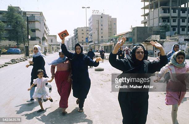 Lebanese women and children run away from combat between the Hezbollah and Amal militia.