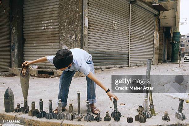 Young boy is displaying pieces of rockets, grenades and other weapons at a street corner in Beirut.