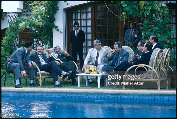 Yasser Arafat sits on the pool side in the garden of his Casablanca villa with seven other people while two bodyguards keep an eye on them during the...