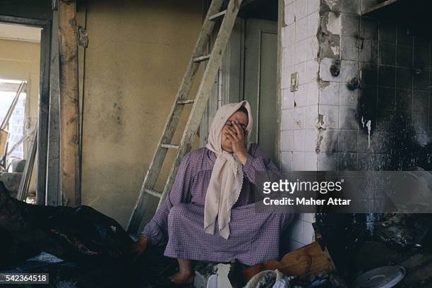 Woman sits crying with her belongings, in a ruined building from the West Beirut bombings.