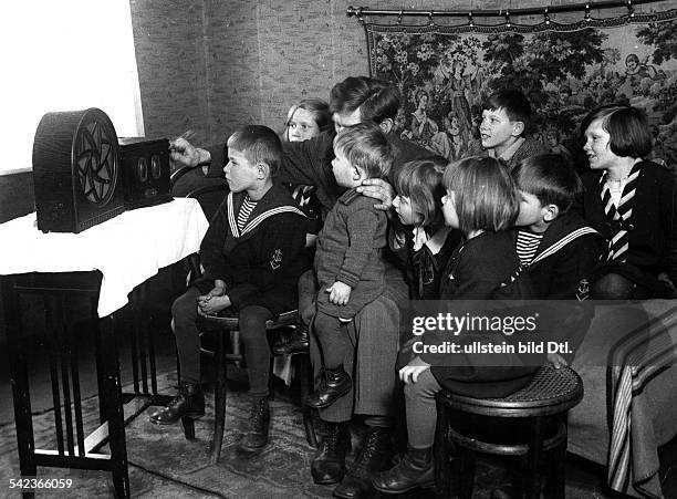 Child images A father and his many children listening to the radio - photo: Der Reporter - 1933 - Vintage property of ullstein bild