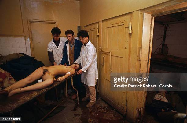 Medical staff examine the body of a dead woman while other corpses of riot victims are piled on the floor in an ante-room of the Forensic Institute...