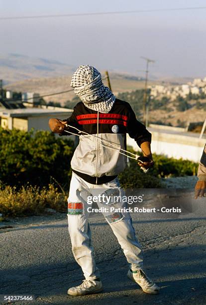 Masked Palestinian man carries a sling used to fling rocks during a riot in Shufat, Jerusalem. The riot is in response to a shooting by a discharged...