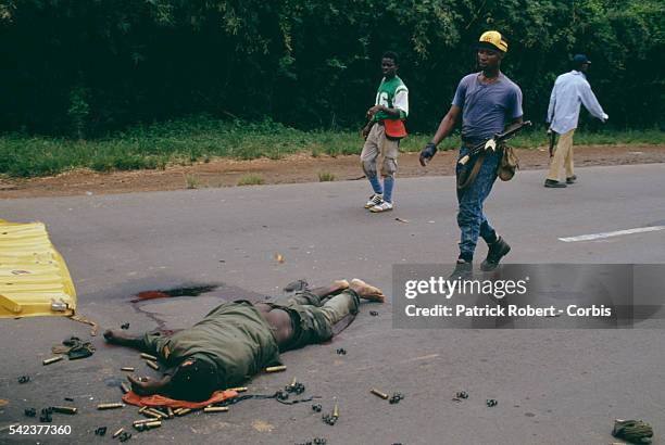 Member of the National Patriotic Front of Liberia walks towards a dead government solder lying in the road. Responding to years of government...