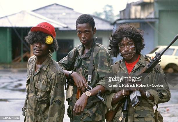 Three young member of the Independent National Patriotic Front of Liberia dress themselves in wigs and face paint, an act often done by rebel forces...
