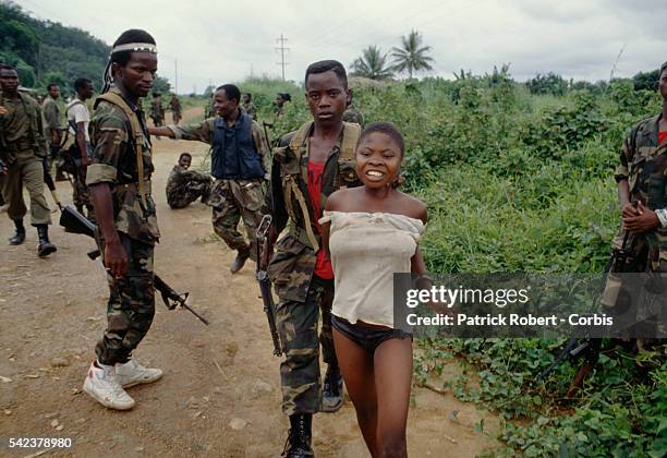 Members of the Independent National Patriotic Front of Liberia hold a civilian woman prisoner for giving food to enemy forces. Responding to years of...