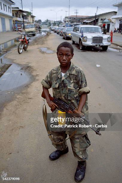 Young child, one of many coerced into serving with the rebel factions, patrols the streets of Monrovia as part of the Independent National Patriotic...