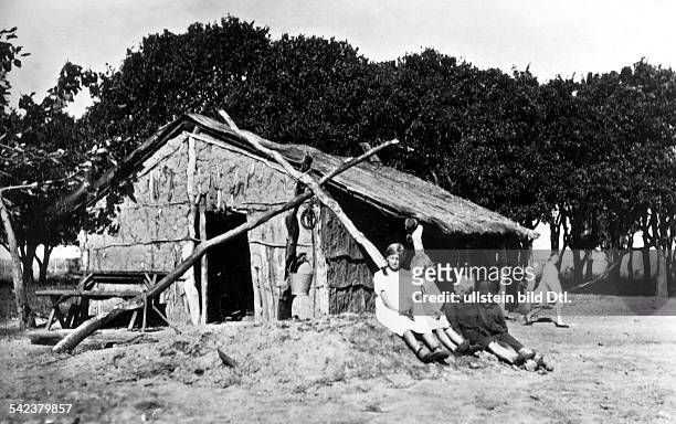 Die Kinder europäischer Einwanderersitzen vor einem aus Lehm gebautenHaus in einer Apfelsinenplantage- 1928