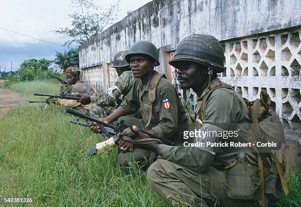Soldiers squat behind a wall during the Liberian Civil War. The AFL is the national army under the Samuel Doe regime. By 1992, the AFL maintained...