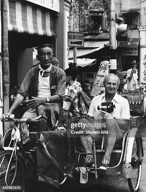 Tourist mit Filmkamera in einer Fahrrad-Rikscha in Singapur- 1980