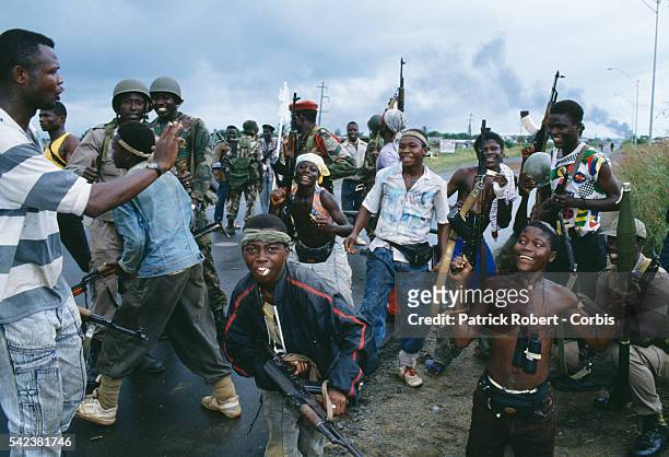 Young rebels pose and display their weapons as they chat with ECOMOG soldiers in Monrovia during the Liberian Civil War. In 1989, Charles Taylor,...