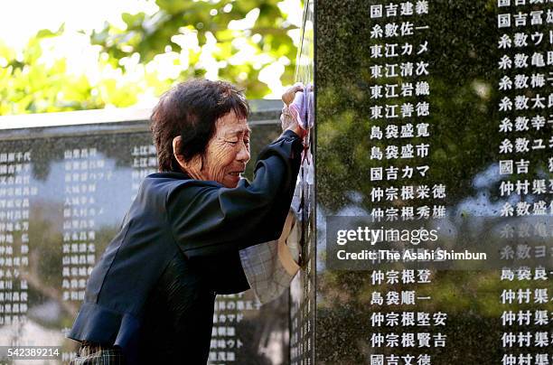 Woman sobs as she touches the name of her deceased brother engraved in the Cornerstone of Peace monument at a ceremony marking the 71st anniversary...